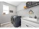 Bright laundry room featuring modern washer/dryer, utility sink, storage, and window for natural light at 640 Bayern Ln, Debary, FL 32713
