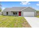 Well-maintained single-story home with a two-car garage, a red front door, and fresh landscaping at 654 Ne 130Th Ct, Silver Springs, FL 34488