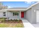 Charming home featuring a bright red door, lush landscaping, and freshly painted exterior at 654 Ne 130Th Ct, Silver Springs, FL 34488