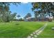 Manicured backyard with mature trees, a fire pit, screened in back porch, and stepping stone path at 6790 Bay Shore Dr, St Cloud, FL 34771