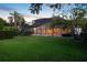 Lush green backyard at dusk with a screened-in patio, columns, and an overhead screen at 9142 Southern Breeze Dr, Orlando, FL 32836