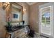 Powder room with decorative mirror, ornate vanity, and access to outdoor pool at 9142 Southern Breeze Dr, Orlando, FL 32836