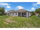 The back exterior of the house features a screened lanai and a well-manicured backyard under a blue sky at 10151 Chorlton Cir, Orlando, FL 32832