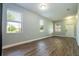 Open living room with hardwood floors, three sunny windows with shades, and a white door at 11081 Savannah Landing Cir, Orlando, FL 32832