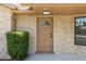 Close-up of a tan front door with decorative window, surrounded by brick and trimmed bushes at 1299 Buccaneer Ave, Deltona, FL 32725
