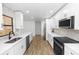 Modern kitchen with white cabinets, stainless steel appliances, tiled backsplash and wood-look floors at 1299 Buccaneer Ave, Deltona, FL 32725