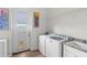 Bright laundry room with sink, washer, dryer, painted mural, door to the outside, and shelf above the units at 13023 Sweet Hill Rd, Polk City, FL 33868