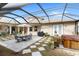 Screened patio with dining set, grill, and hot tub, all overlooking the manicured lawn and lush landscaping at 13023 Sweet Hill Rd, Polk City, FL 33868