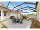 Screened patio with umbrella table and chairs, grill, and jacuzzi, with a clear view of the backyard and greenery at 13023 Sweet Hill Rd, Polk City, FL 33868