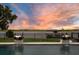 Stunning lake view from the pool area, enhanced by fire bowls, a wrought iron fence, and a dock, set against a vivid sunset at 15787 Tangerine Dream Ct, Winter Garden, FL 34787