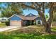 Charming single Gathering home with a beautiful blue exterior, mature trees, and a well maintained lawn at 171 Cedarpark Ln, Davenport, FL 33837