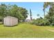Large, green backyard featuring a storage shed with lush trees and greenery around perimeter at 214 S Cottage Hill Rd, Orlando, FL 32805