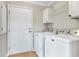 Bright laundry room features Maytag machines, overhead cabinets, and a door to the exterior at 28 N Osceola Ave, Center Hill, FL 33514