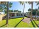 A green backyard with trees, a pool, an outdoor dining area, and a screened-in porch at 418 Acacia Cir, Port Orange, FL 32127