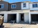 New townhouse construction showing the two-story facade and garage entrance, unfinished yard in front, and a blue sky above at 4224 Campsite Loop, Orlando, FL 32824