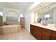 Bright bathroom featuring a large soaking tub and double vanity sink with wooden cabinets at 436 Skyview Pl, Chuluota, FL 32766