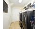 Spacious laundry room with modern washer and dryer, storage shelves, and tile flooring at 436 Skyview Pl, Chuluota, FL 32766