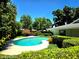 Serene kidney-shaped pool surrounded by lush greenery, creating a private and tranquil backyard oasis at 5096 The Oaks Cir, Orlando, FL 32809