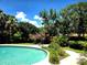 Lush backyard oasis featuring a sparkling swimming pool, mature trees, and serene landscaping at 5096 The Oaks Cir, Orlando, FL 32809