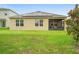 Backyard view of the house featuring a screened-in patio, solar panels, and well-maintained lawn at 522 Anne St, Deland, FL 32724