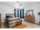 Bedroom with ceiling fan, wood-look floors, dresser, and natural light from a large window at 7454 Gathering Dr, Reunion, FL 34747