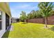 Expansive backyard with lush green grass, privacy wall, and a screened-in patio in view at 977 Talon Pl, Winter Springs, FL 32708