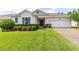 Charming single-story home with lush green lawn, manicured shrubs, and a brick driveway leading to the attached garage at 977 Talon Pl, Winter Springs, FL 32708