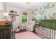 A delightful Bedroom featuring floral wallpaper, a gold crib, and soft pink accents for a cozy feel at 1033 Mccully Ct, Oviedo, FL 32765