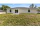 Rear exterior view of a single-story home with sliding glass doors and a spacious grassy yard at 13031 Ne 7Th Loop, Silver Springs, FL 34488