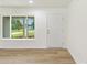 Bright and airy living room featuring wood-look floors, fresh paint, and a large window with a view of the outdoors at 13031 Ne 7Th Loop, Silver Springs, FL 34488