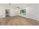 Well-lit living area with wood-look floors, ceiling fan, and a door to the left to another room at 13031 Ne 7Th Loop, Silver Springs, FL 34488