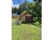 Detached garage with wood doors surrounded by lush greenery and a white picket fence at 1307 Mabbette St, Kissimmee, FL 34741