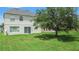 Spacious backyard featuring a large tree, lush green lawn, and a rear exterior view of the property at 1509 Cedar Lake Dr, Orlando, FL 32824
