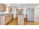 Bright kitchen with center island, wood-look floors, stainless-steel refrigerator, and white appliances at 16053 Wilkinson Dr, Clermont, FL 34714