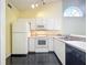 Bright kitchen with white cabinets, appliances, black tile flooring, and a sunny arched window at 1751 Chatham Cir, Apopka, FL 32703