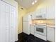 Compact kitchen features white appliances, cabinets, black tile flooring, and ample storage space at 1751 Chatham Cir, Apopka, FL 32703