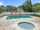 Relaxing pool area featuring a hot tub, well-manicured landscape, and a secure white fence, creating an oasis for enjoyment at 1751 Chatham Cir, Apopka, FL 32703