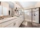Modern bathroom with double sinks, granite countertops, a large mirror, and a glass-enclosed shower at 1789 Chatsworth Cir, St Cloud, FL 34771