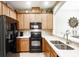Well-equipped kitchen with black appliances, wooden cabinetry, and a view into the living area at 1941 Sunset Palm Dr, Apopka, FL 32712