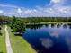 Aerial shot featuring a walking path along the edge of a tranquil pond reflecting the blue sky with fluffy white clouds at 1941 Sunset Palm Dr, Apopka, FL 32712