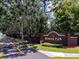 Entrance sign to Wekiva Park Townhomes, featuring a brick structure, mature trees, and a walking path at 1941 Sunset Palm Dr, Apopka, FL 32712