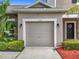 Attached garage with an automatic door is framed by a garden with red mulch and shrubs at 2092 Switch Grass Cir, Ocoee, FL 34761