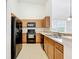 Galley kitchen with wood cabinets, black appliances, and tile flooring at 2092 Switch Grass Cir, Ocoee, FL 34761