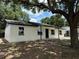 A bright white house with black accents and a dark roof stands on a lush lawn beneath the shade of a tree at 212 Dorothy St, Auburndale, FL 33823