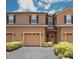 Charming townhome featuring a two-car garage, shuttered windows, and a welcoming entrance with tasteful landscaping at 2241 Retreat View Cir, Sanford, FL 32771