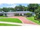 Charming single-story home with a brick driveway, attached garage, manicured lawn, and lush landscaping at 2527 Shrewsbury Rd, Orlando, FL 32803