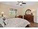 Cozy bedroom featuring a bed with patterned bedding, warm neutral paint, wood floors, and decorative furniture at 2759 Purple Meadow Ct, Minneola, FL 34715