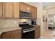 Close-up of kitchen showing stainless steel microwave, gas range, granite countertops, and wood cabinets at 2759 Purple Meadow Ct, Minneola, FL 34715
