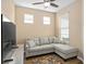 Comfortable living room featuring a grey sectional sofa, ceiling fan, and a large TV for relaxation at 2759 Purple Meadow Ct, Minneola, FL 34715