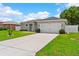 Well-maintained home with a spacious driveway and lush green lawn under a sunny sky at 308 Clearwater Ln, Poinciana, FL 34759